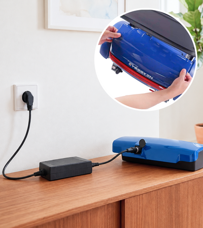 Blue air compressor on a wooden surface with a wall outlet in the background